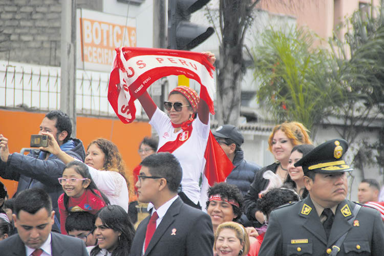 (5) ORGULLOSA. Entre el mar de asistentes, mujer vestida con los colores patrios flamea una bandera.