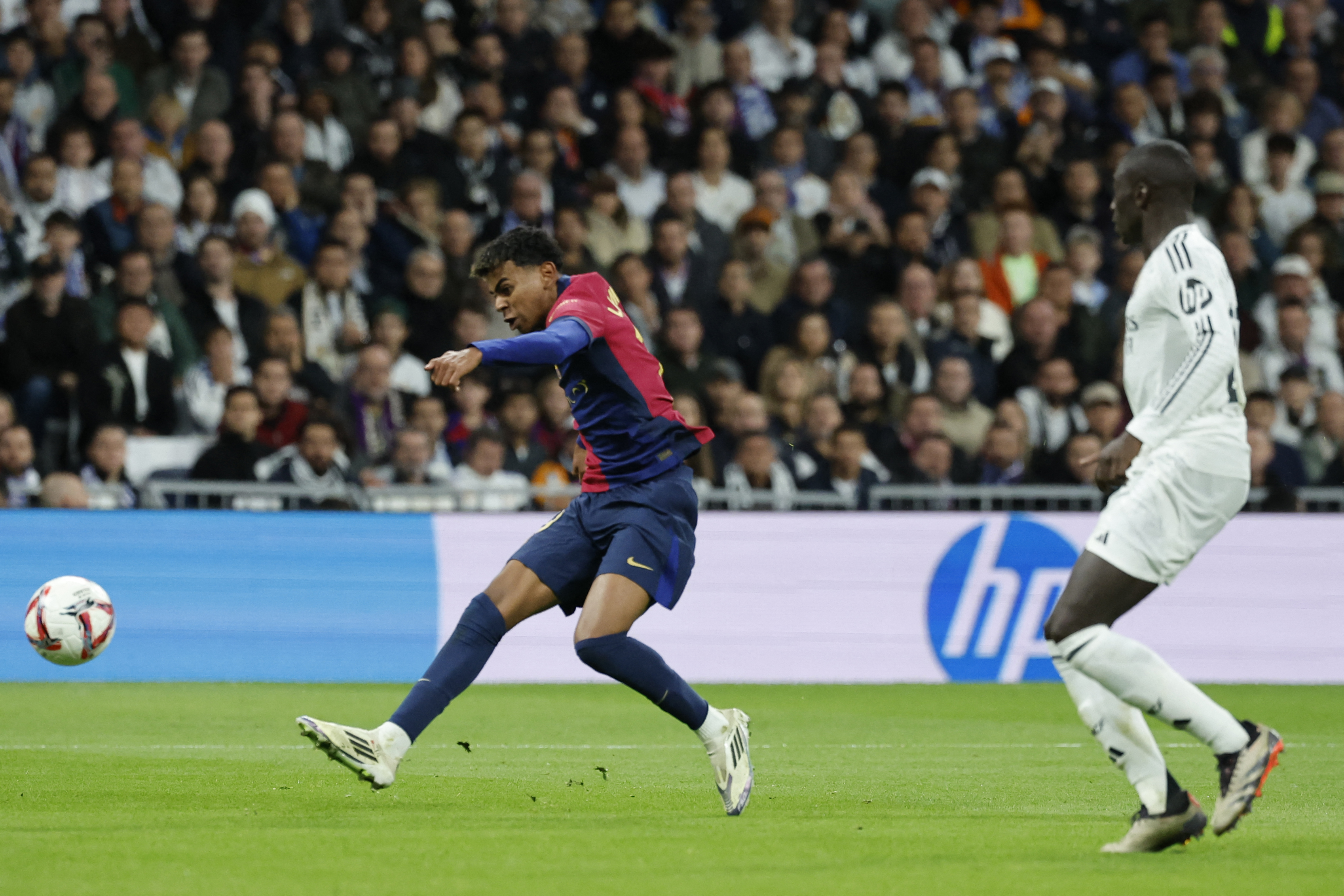 El delantero español #19 del Barcelona, ​​Lamine Yamal, marca el tercer gol de su equipo durante el partido de fútbol de la liga española entre el Real Madrid CF y el FC Barcelona en el estadio Santiago Bernabéu de Madrid el 26 de octubre de 2024. (Foto de OSCAR DEL POZO / AFP)