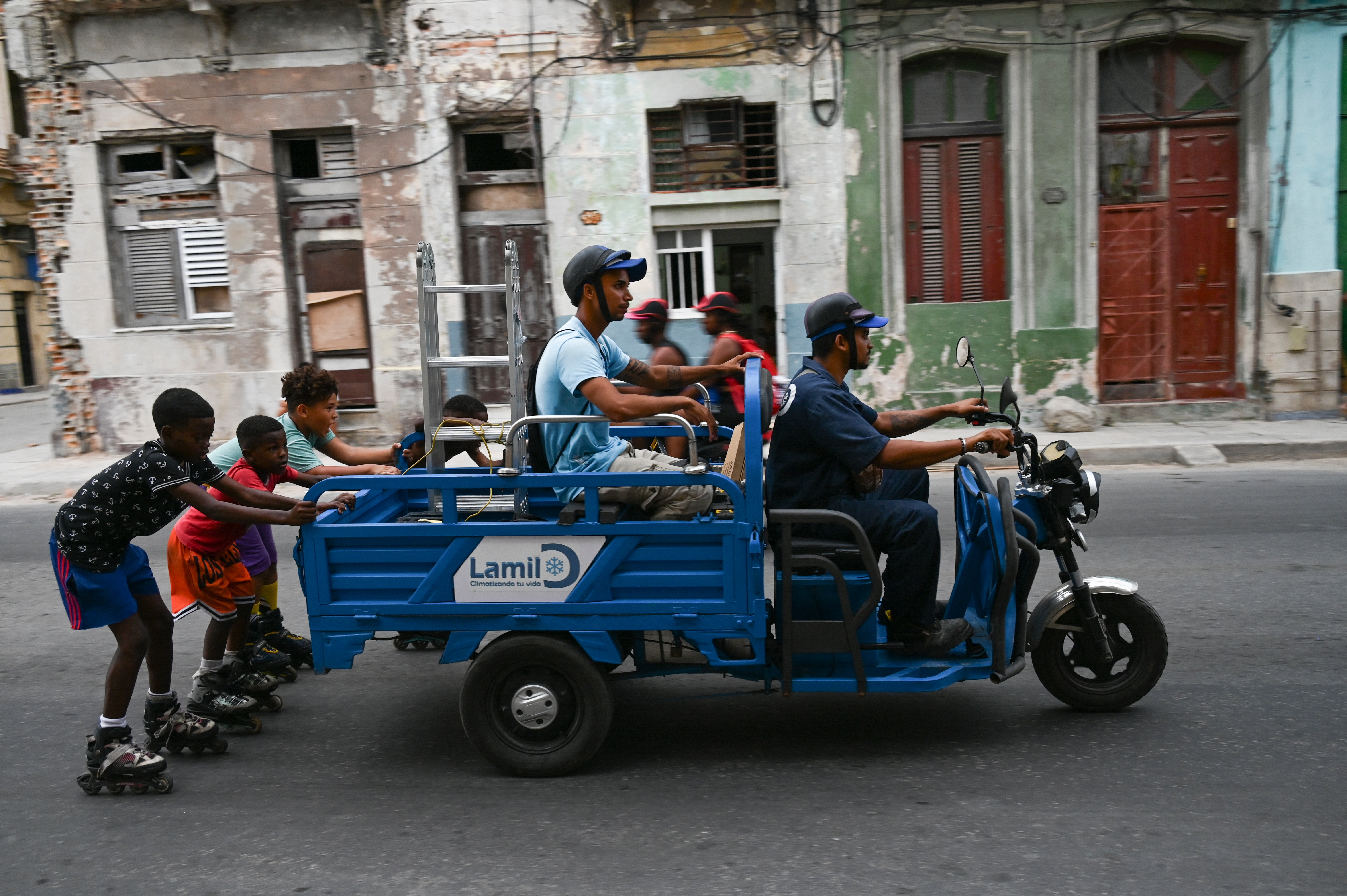 El ministro de Energía y Minas de este país señaló que el servicio estaría restablecido para la noche de este lunes. (Foto: Niños en patines se cuelgan de un carro durante el tercer día de un apagón masivo en La Habana el 20 de octubre de 2024/ AFP).