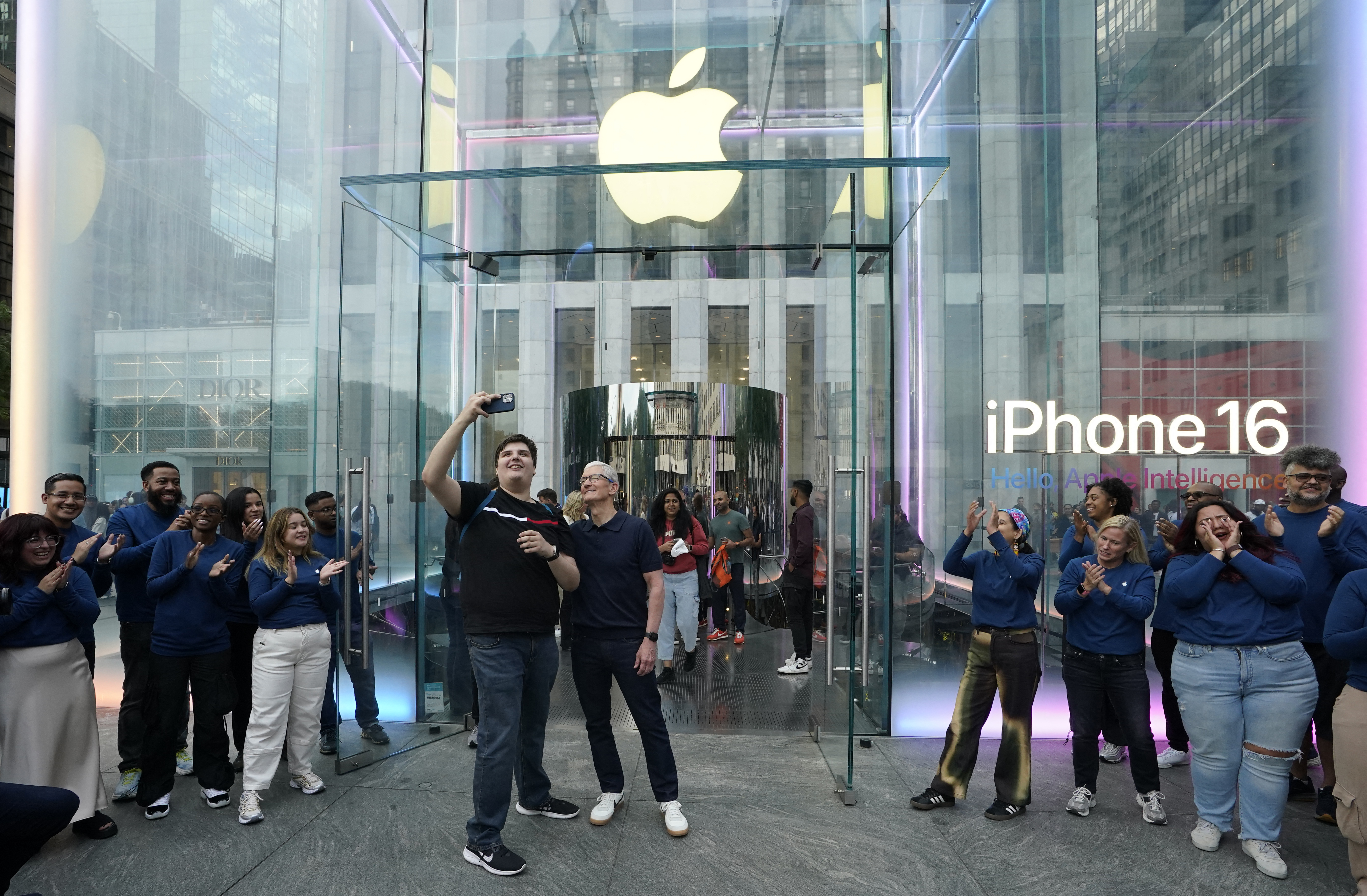 Apple CEO Tim Cook (C) poses for selfies with customers during Apple's iPhone 16 launch in New York on September 20, 2024. Apple on September 9, 2024 announced a new iPhone built for generative artificial intelligence as it seeks to boost sales and show it is keeping up in the technology race. (Photo by TIMOTHY A. CLARY / AFP)